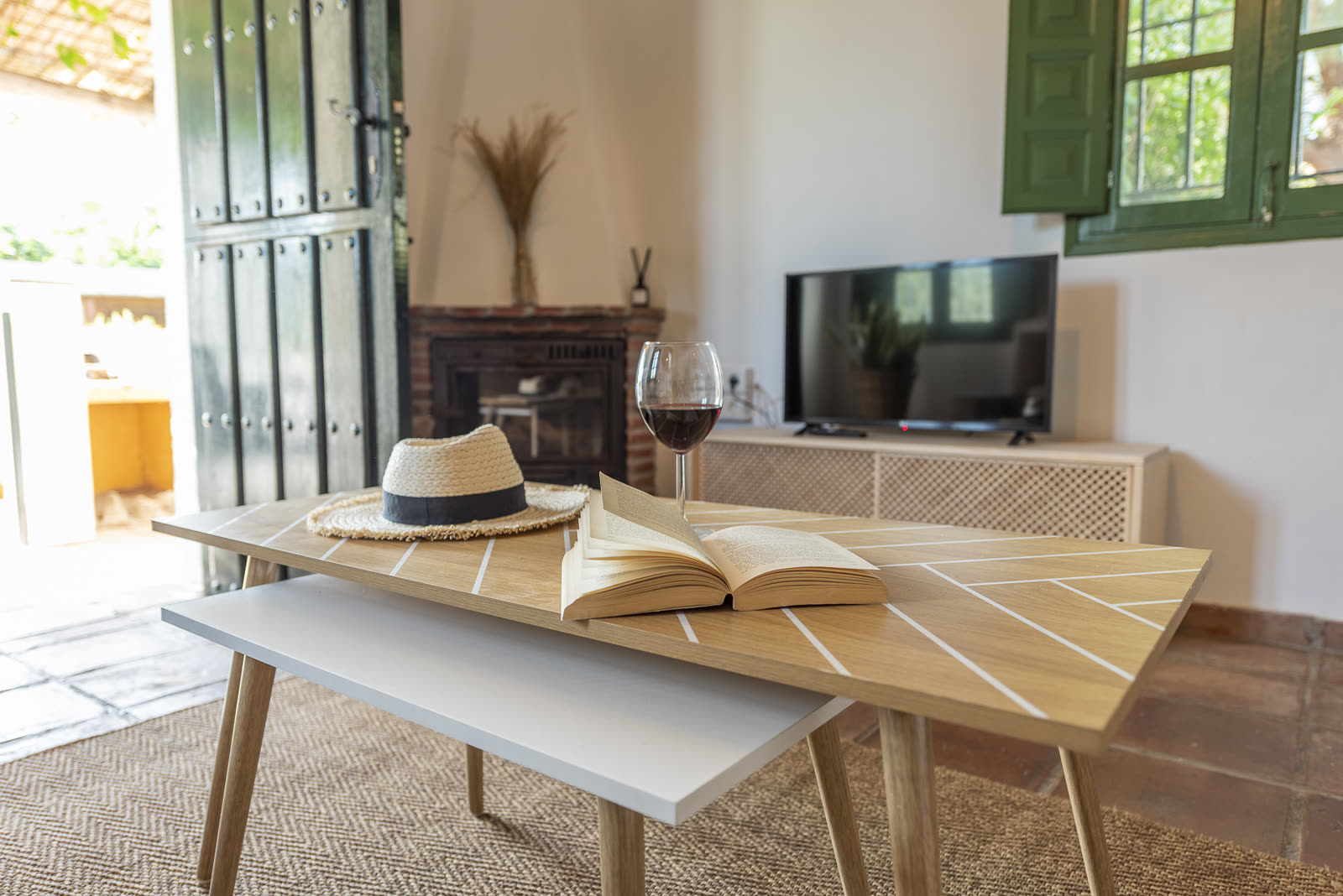 Coffee table with a book, hat and glass of wine by the fireplace