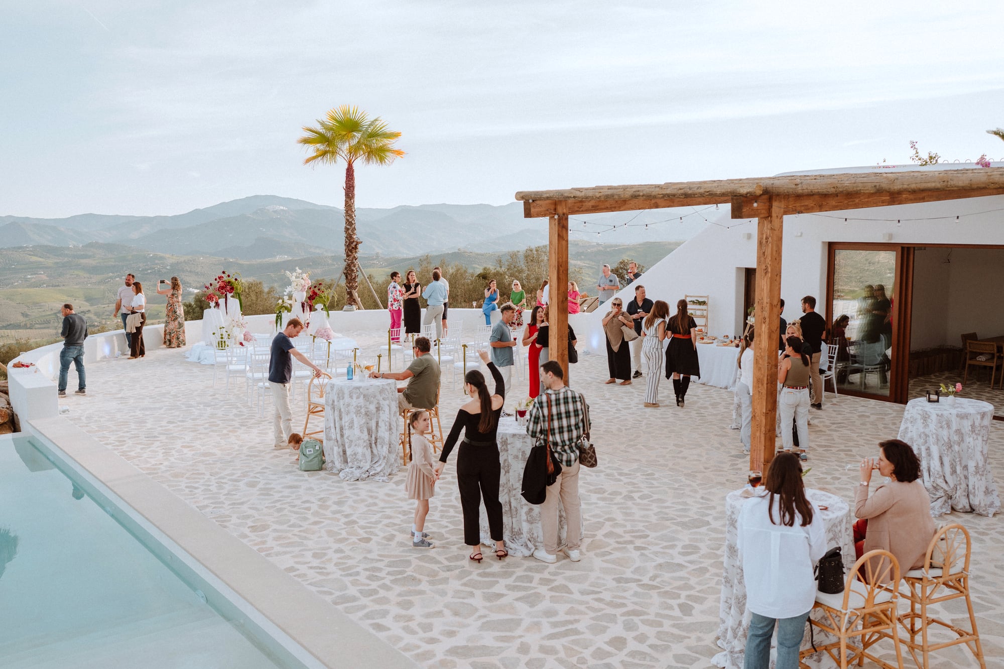 Guests at a celebration on the pool terrace with mountain views