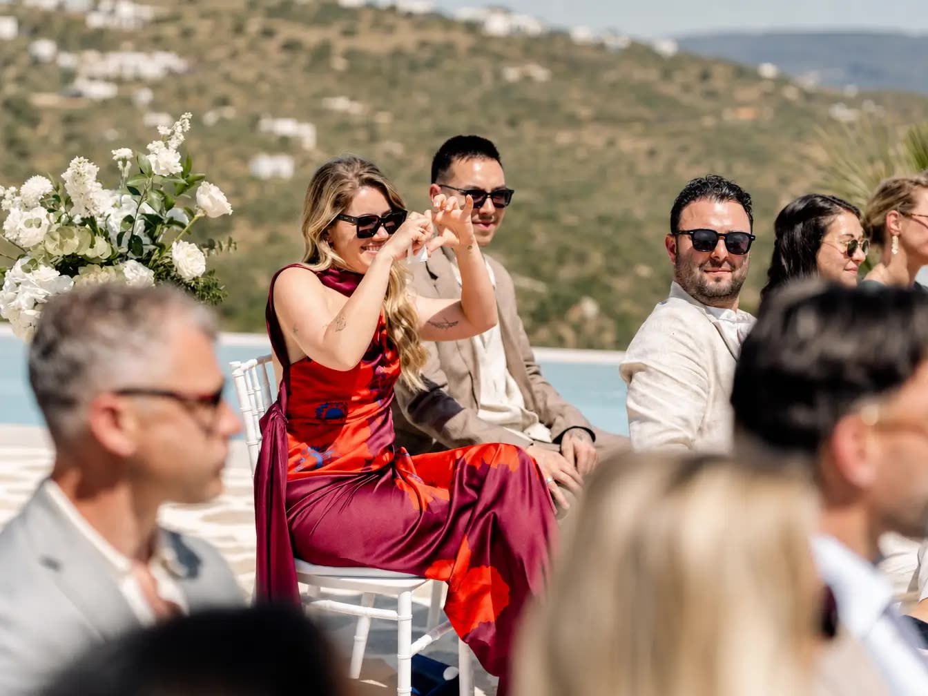 Wedding guest in a red dress smiling during the ceremony
